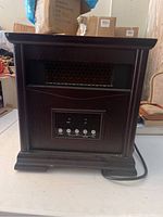 Front view of the infrared heater showing wooden casing, honeycomb mesh heating area, and front control panel.