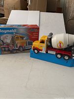 Toy cement truck shown with its box on a white background.