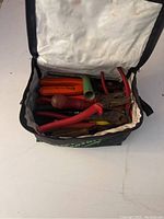Soft carrying bag filled with hand tools including pliers and screwdrivers
