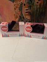 Two boxed pairs of Totes Toasties memory foam slippers, one leopard print and one black, both size large 8-9.