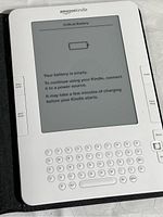 Close-up of the white Amazon Kindle displaying a critical battery message on e-ink screen.