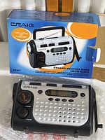 Radio in original retail box showing front and side features, including flashlight and crank handle.