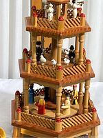 Overall front and side view of the three-tier decorated Christmas pyramid carousel with hand-painted figurines including people and animals.
