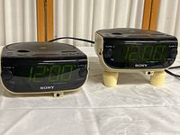 Two vintage Sony Dream Machine clock radios showing front digital green LED displays set to 12:00, with alarm settings visible.