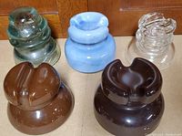 Five antique insulators in different colors and materials placed on a flat surface