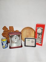 Photo showing all items including glass desk clock, wooden plates, digital radio/weather station and decorations with a can included for scale