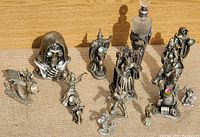 Overview of the pewter fantasy figurines showing a skeleton hooded figure with green eyes, wizards, warrior on throne, and mythical dragons with glass insets.