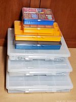 View of stacked plastic storage containers showing variety of sizes and colors with hardware inside compartments.