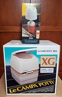 LeCampa Porta Potti XGL packaged with table lantern box on wooden background.