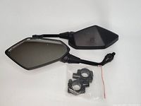 Pair of new black plastic enclosed motorcycle rearview mirrors with alloy retainers and mounting hardware in a clear plastic bag.