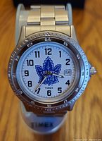 Front view of Timex watch showing Toronto Maple Leafs logo, analogue time display with Arabic numbers, date window, and stainless steel band.