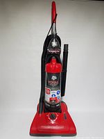 Full view of the red Dirt Devil Total Vision upright vacuum cleaner with hose and cleaners.