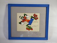 Full view of framed cel showing Goofy roller skating in blue frame with matting and signature.