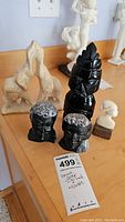 All items arranged on a wooden table showing the entire lot including the tiki god statue, bust figurines, elephant, and praying hands sculpture