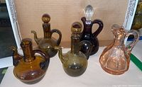 Five assorted colored glass oil bottles displayed on a surface inside cardboard box background.