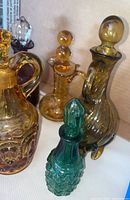 Five assorted colored glass oil bottles with stoppers displayed on a white surface