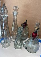 Front angled view of 5 glass oil bottles with stoppers on a white surface against a cardboard background.