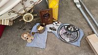 Overview of the lot showing all items together including clock, dog figure, brass watering can, wall art, teapot and tray.