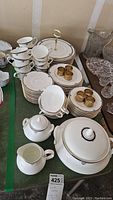 Assorted plates, cups, bowls, tureen, serving stand and napkin rings arranged on table
