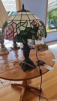 Both lamps on wooden table under window