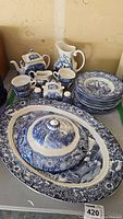 All items arranged together, showing full set including teapot, pitchers, cups, plates, shakers, and covered platter.
