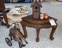 Photo showing carved wooden corner table with claw feet, horse figurine next to it, birdhouse and decorative eggs on the table.