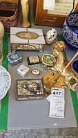 Overview of brass carousel horse music box on right, assorted small decorative trinket and jewelry boxes including egg-shaped and rectangular boxes on table