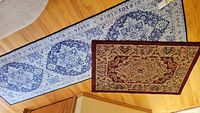 Both rugs laid flat on wood floor showing size difference and design differences.