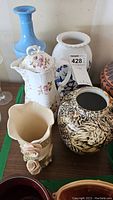 Photo showing six ceramic vases and one pitcher with various colors and floral designs.