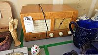 Vintage Grundig wooden clock radio on display with some surrounding items.