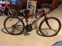 Side profile showing the entire bike, highlighting the dark red frame, tire tread, and drivetrain with chainrings and derailleur.