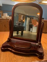 Front view of antique dresser top mirror showing rounded rectangular mirror with cherry wood frame and scalloped base