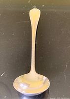Top view of electroplated silver gravy spoon showing feather edged handle