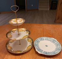 Full view of the Royal Falcon Ware 3-tier cake stand featuring a yellow rose floral pattern and one blue tree design platter on the side.