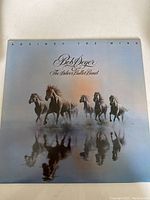 Front cover of vinyl LP showing five horses running with reflections on water, title and artist name in cursive script.