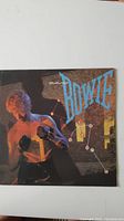 Front cover of David Bowie's 'Let's Dance' vinyl album showing Bowie in a boxing pose with colorful lighting and logo text.