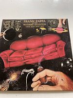 Front cover of 'One Size Fits All' vinyl album featuring surreal artwork with a red sofa in space, planets, and a hand with a cigar.
