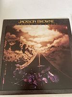 Front cover of the vinyl album showing the road and drum set image with 'Jackson Browne Running On Empty' text.
