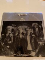 Front cover of Queen 'The Game' vinyl album showing the band members in black and white on a silver background.