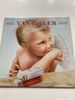 Front cover of the Van Halen 1984 vinyl record showing painting of a blond angelic child with cigarette and pack of cigarettes labeled MCMXXXIV.