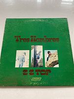 Front cover of Tres Hombres vinyl record showing album title, band name, and photographs of band members.