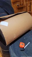 Large roll of acoustic cloth wrapped in brown paper, measuring tape beside it for scale.