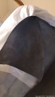 Close-up of dark gray textured acoustic cloth corner inside wrapping, showing fabric texture.