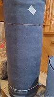 Full view of the rolled acoustic cloth standing upright, showing its length and consistent dark blue tone.