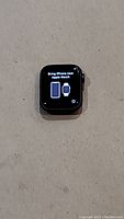Apple Watch SE smart watch screen showing 'Bring iPhone near Apple Watch' prompt on a plain surface.
