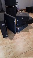 Four transport cases stacked and spread on floor, showing metal corners, cloth covering, and handles.