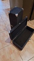 Two rectangular cases, one standing and one open showing black felt interior, all covered in gray acoustic cloth with metal corners and hinges