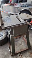 Full view of the metal table saw sitting on a stand, showing overall construction and condition.