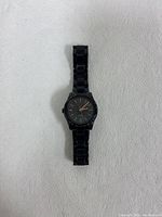 Front view of black Fossil watch with gold hands and markers on a black dial, metal link bracelet band.