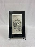 Front view of the framed possum artwork on a stand, showing the detailed black-and-white illustration and artist signature.